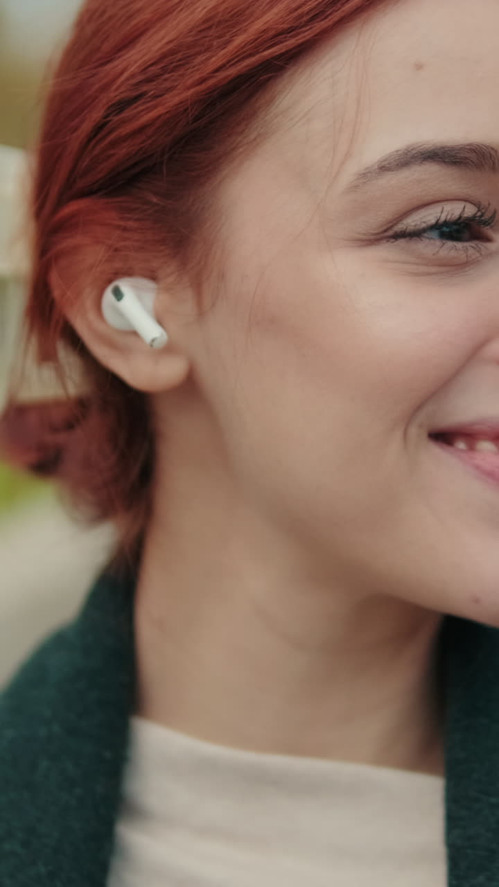 Primo piano di una giovane donna sorridente con auricolare wireless