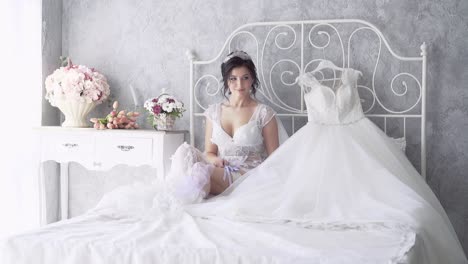 la novia en cámara lenta con vestido de encaje se sienta cerca del vestido de novia