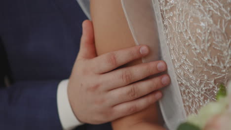 Man-strokes-arm-of-beloved-bride-wearing-glam-wedding-dress