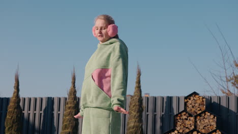 woman in green outfit with pink earmuffs