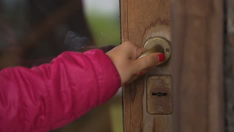 4k cerca de la mano femenina chaqueta rosa abriendo la puerta de la casa de madera