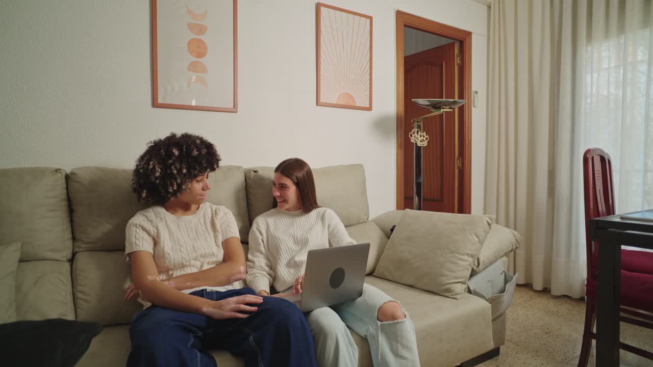 Duas mulheres sentadas em um sofá com um laptop