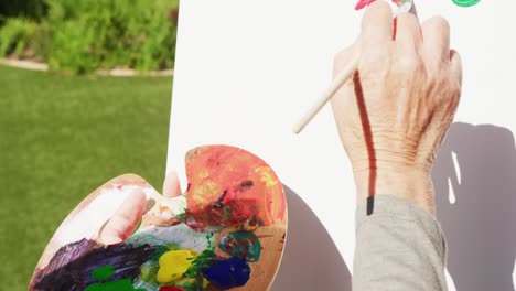 Close-up-of-asian-senior-woman-painting-in-garden-on-sunny-day