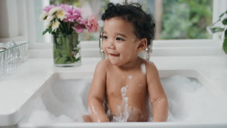 bebé feliz bañándose niño pequeño divertido bañándose en el fregadero de la cocina divirtiéndose con burbujas de jabón 4k