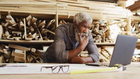 african american male carpenter using laptop at a carpentry shop