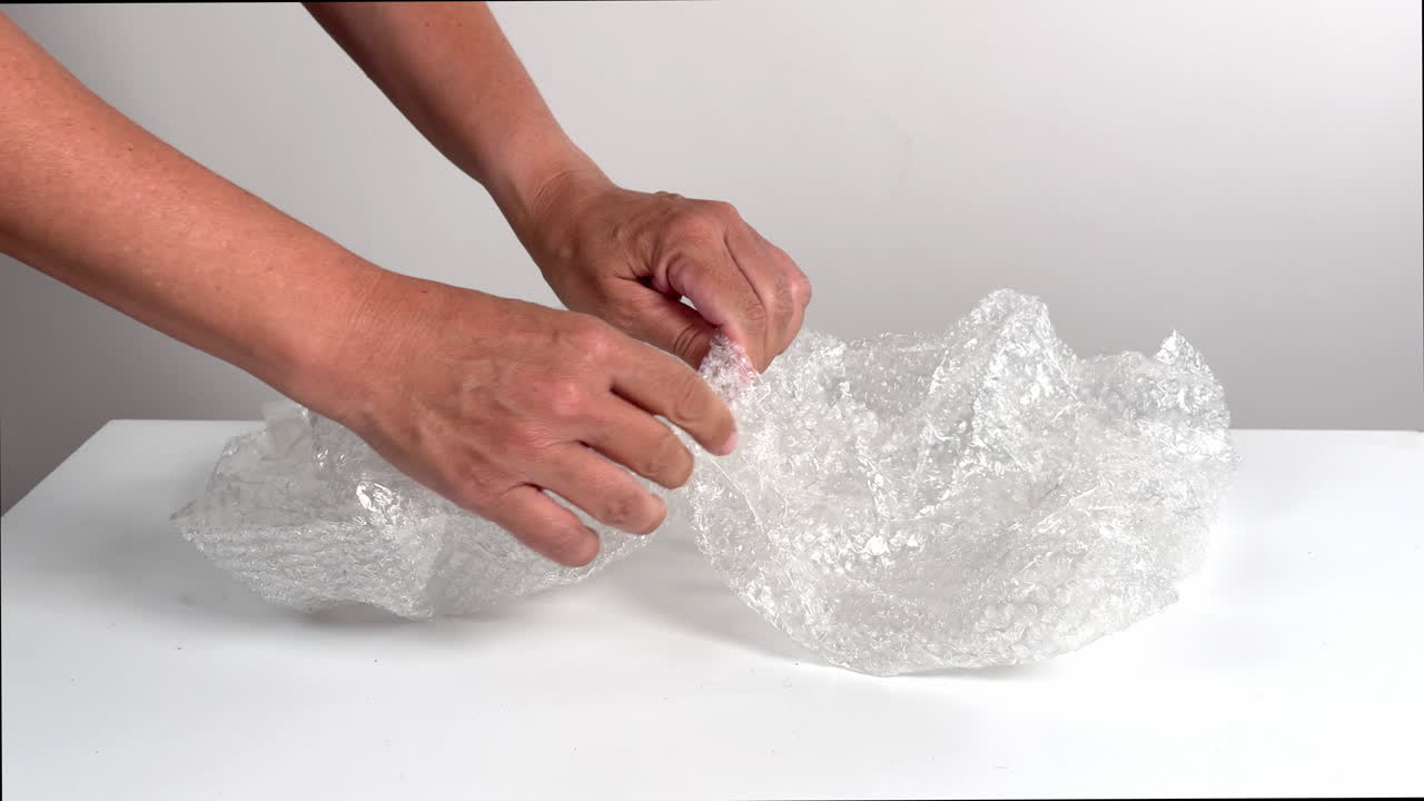 Hands Popping Bubble Wrap on a White Table