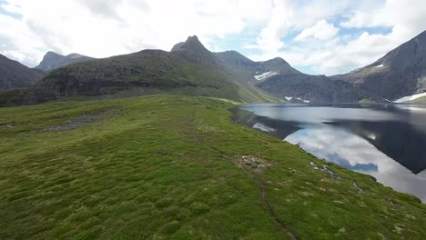 In-a-mesmerizing-journey,-an-FPV-drone-skims-mountain-lakes,-revealing-a-tapestry-of-rugged-peaks-in-a-breathtaking-alpine-panorama