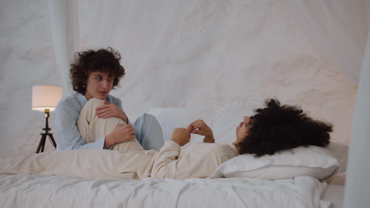 행복 한 부부 가 침대 에서 대화 하고 있다