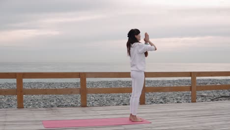 woman practicing yoga on a beach boardwalk