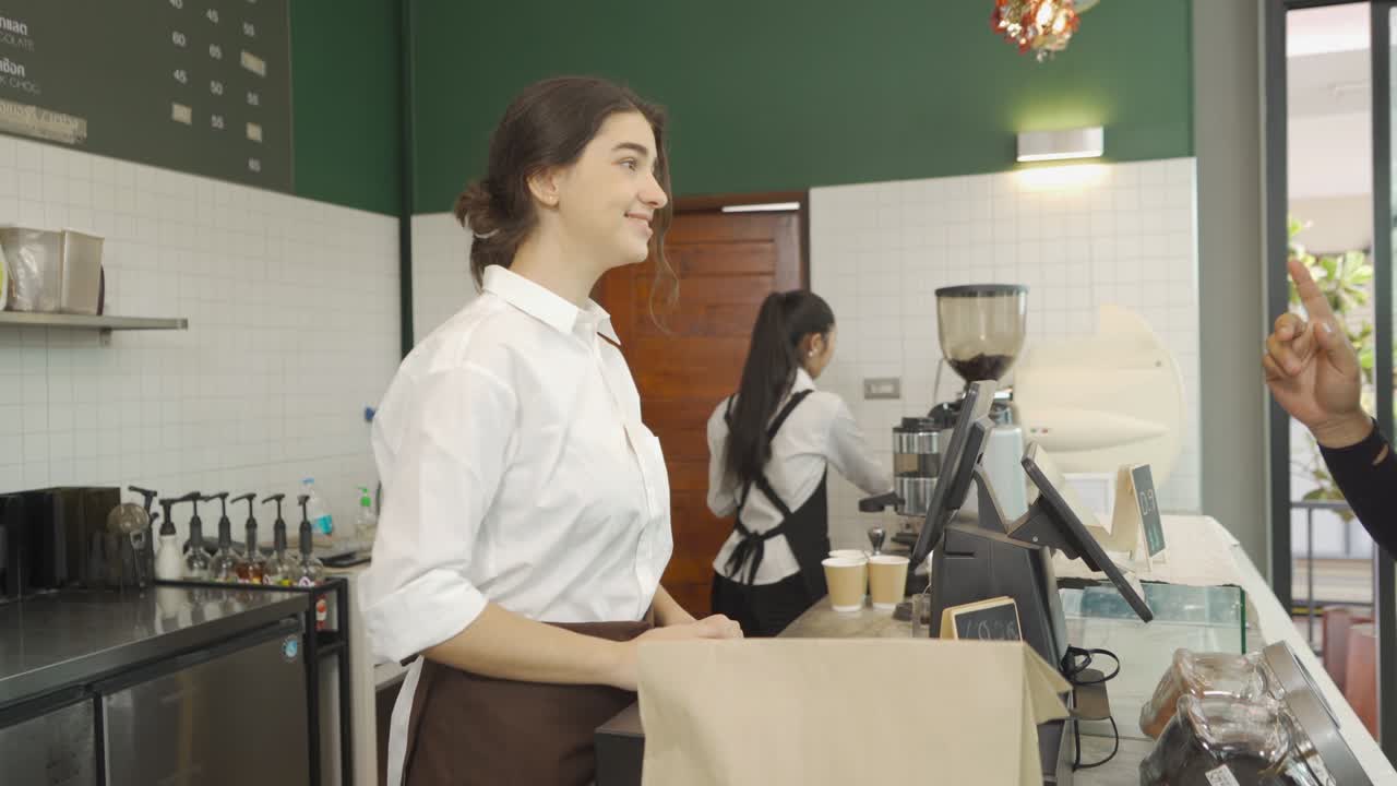 mujer barista del este medio gente en delantal recogiendo un pedido, hablando con el cliente en el mostrador, cafetería caja. servicio de negocios. estilo de vida de la gente.