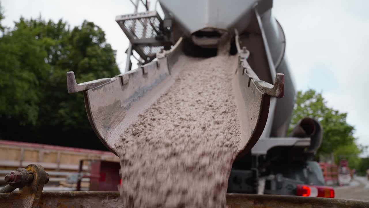 Concrete flows from cement mixer chute, emphasizing construction process. Perfect for urban development projects or educational content on building techniques