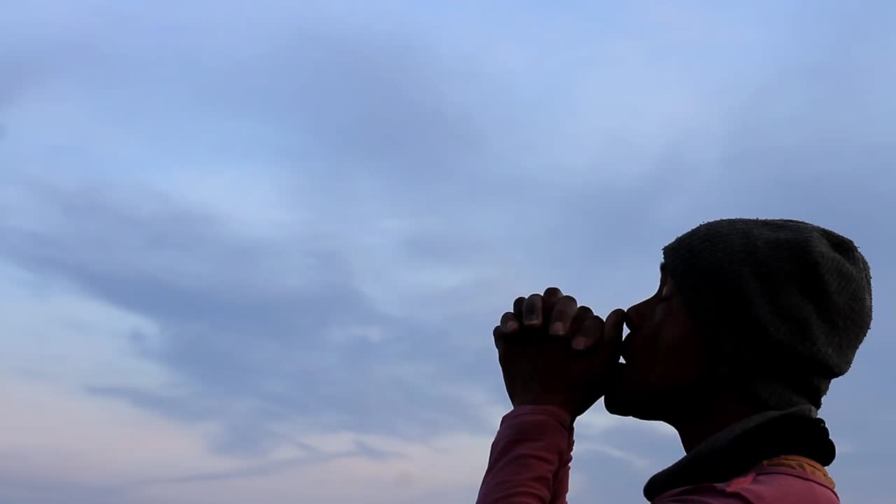 praying to god Caribbean man praying with blue sky in the background stock video