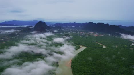 aerial drone shot over patches of cloud with mangrove forest below in phang nga bay, thailand