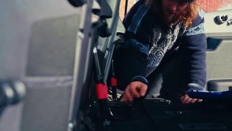 a man works inside a pajero, unscrewing bolts as part of an interior makeover - close up