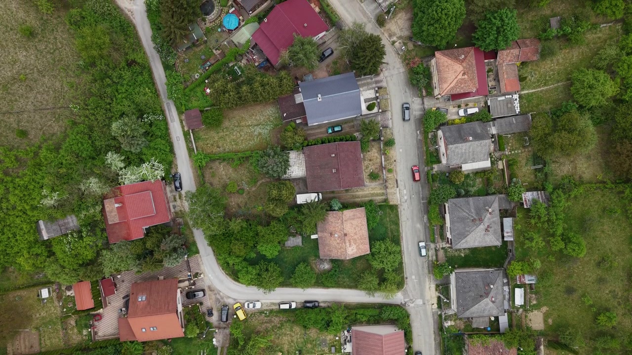 Una prospettiva aerea dall'alto di un quartiere residenziale con case tradizionali, strade tortuose e abbondante vegetazione in una zona tranquilla.