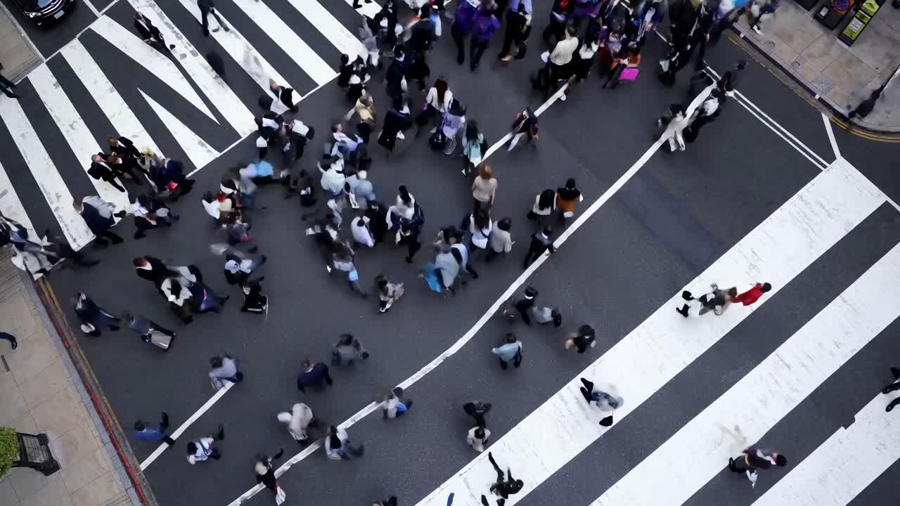 Vista aerea di un trafficato attraversamento pedonale con persone che si muovono in varie direzioni, che cattura la vita urbana