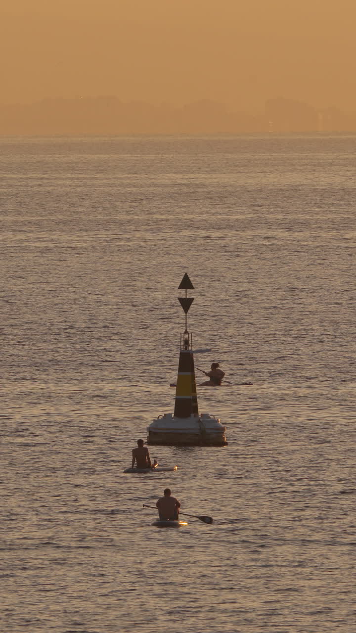 바르셀로나에서 새벽에 그림자 패들 서핑을 하는 사람들이 수직으로