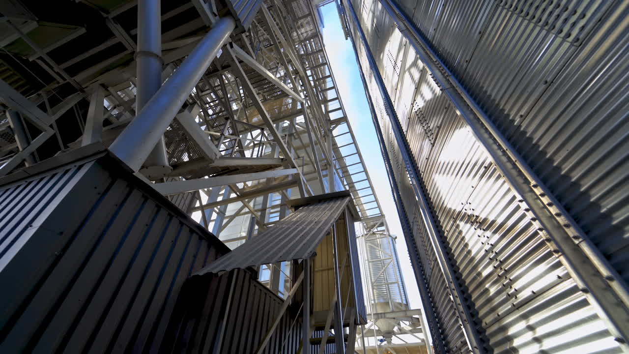 Industrial equipment outdoors. Large metal terminals. Silver grain elevators on a modern plant for storing agricultural products. Close-up.
