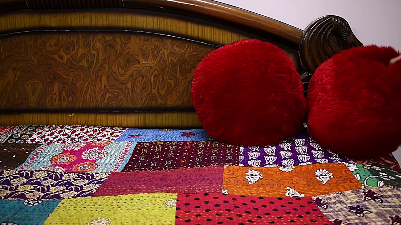 mujer haciendo sobre la cama ajustando la almohada de terciopelo rojo en la cama