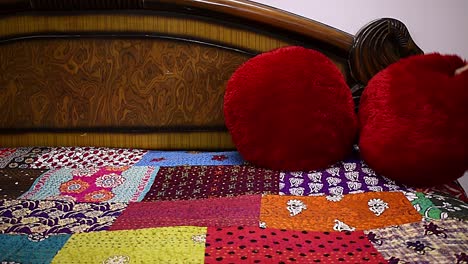 woman making over bed adjusting red velvet pillow on bed