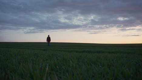 girl walking up a grass hill at sunset