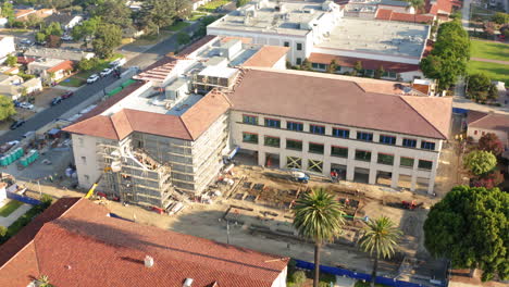 aerial view of a large building undergoing construction with scaffolding and workers