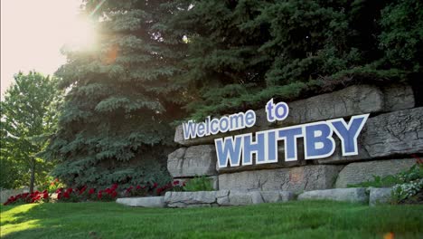 welcome to whitby signage in canada with warming light beaming through the trees with a low angle panning shot