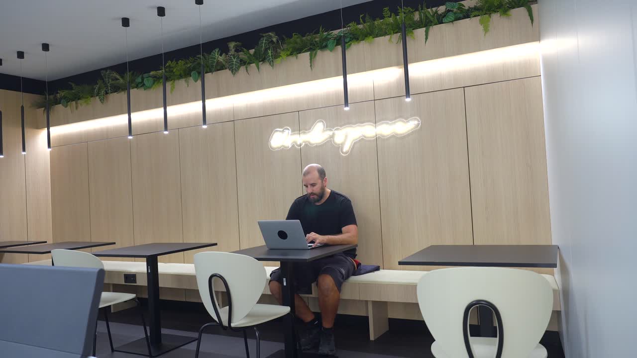 Man Working on Laptop in Modern Cafe