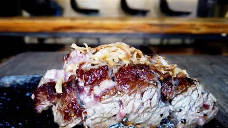 Japanese-steak-steaming-hot-closeup-cooking-on-lava-rock-with-shreds-of-onion-garnish-on-top-and-steaming-coming-out-room-for-text-in-the-top-half-background-vintage-traditional-Japan-style-eatery