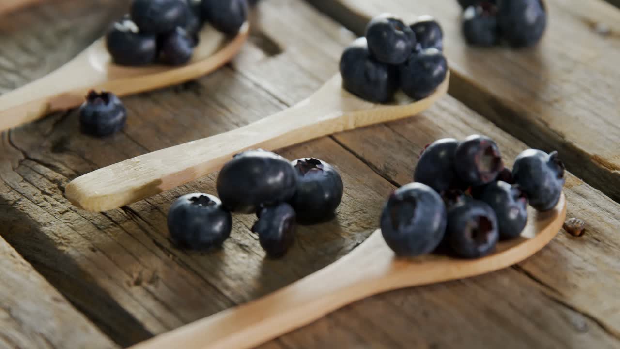 Spoons of blueberries arranged on wooden table 4k