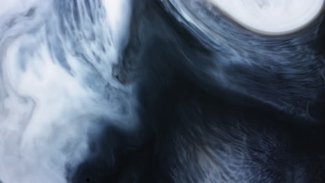 abstract paint swirl moving across mixed black and white liquid in slow motion