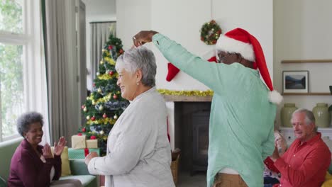 Glückliches,-Vielfältiges-älteres-Paar,-Das-Zur-Weihnachtszeit-Zusammen-Mit-Freunden-Im-Hintergrund-Tanzt