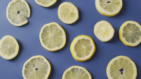 Video-of-slices-of-lemon-lying-on-blue-background