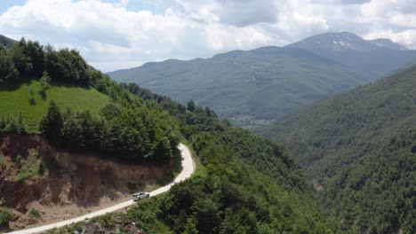 coche blanco sube por una carretera de montaña en la montaña sharr entre la naturaleza verde en un día nublado