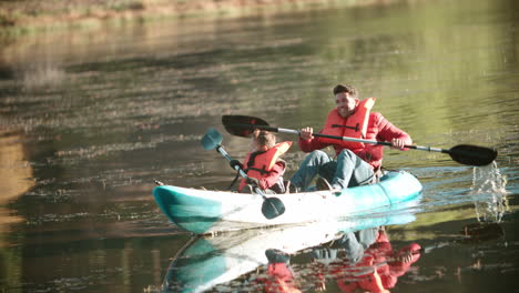 father and son kayaking on a lake during a camping trip