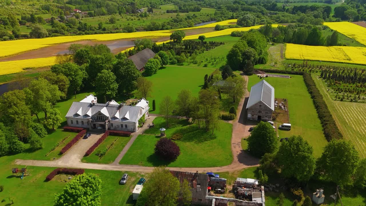 Aerial view of Babtyno Manor, a historic estate surrounded by lush greenery, featuring classic architecture and a well-kept garden. themes related to history, heritage, and countryside estates.