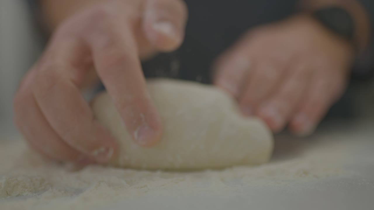 빵 굽는 사람이 신선한 빵 반죽을 반죽하다