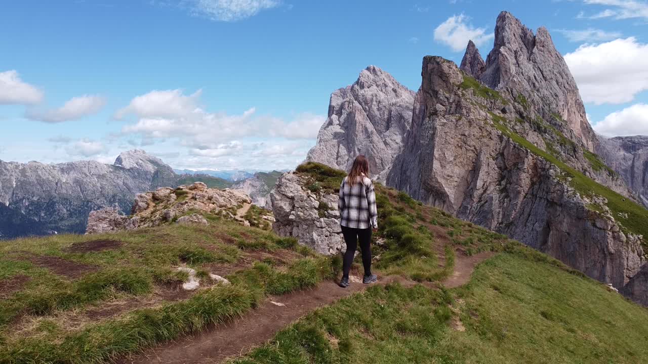 niña caminando por la montaña seceda en urtijei, tirol del sur, alpes italianos, dolomitas, italia - drone vuela hacia adelante