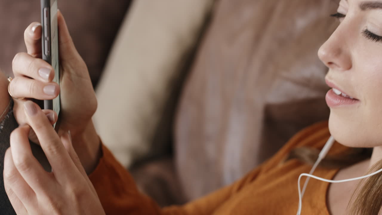 아름다운 여성이 집에서 소파에서 음악을 듣고 편안한 라이프 스타일을 하고 있습니다.