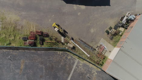 trabajador de fábrica que conecta un producto de acero pesado para ser levantado por una grúa amarilla desde una perspectiva aérea estática