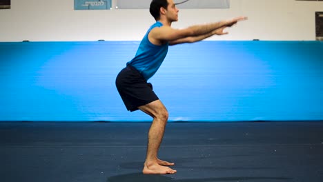 a still shot of a guy doing squats in a gymnastics gym