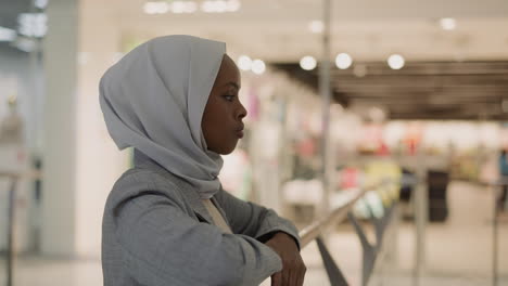 sad african-american woman in hijab leans on level handrail