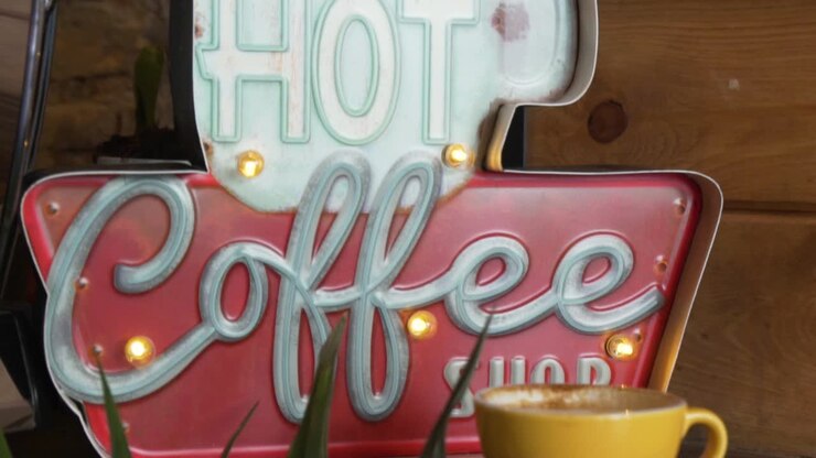 hot-coffee-shop-schild und eine tasse kaffee auf dem display - nahaufnahme