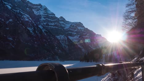 timelapse, hyperlapse shot of a frozen lake in a valley with two huge mountains next to a curvy road