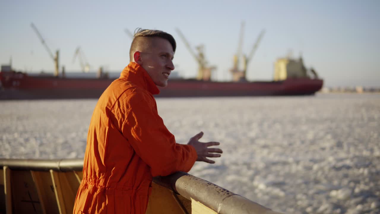 Junger Mann in oranger Uniform reist an Bord des Schiffes im Winter