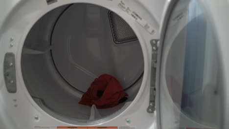 close up of a man loading clothes into a dryer from the washing machine next to it