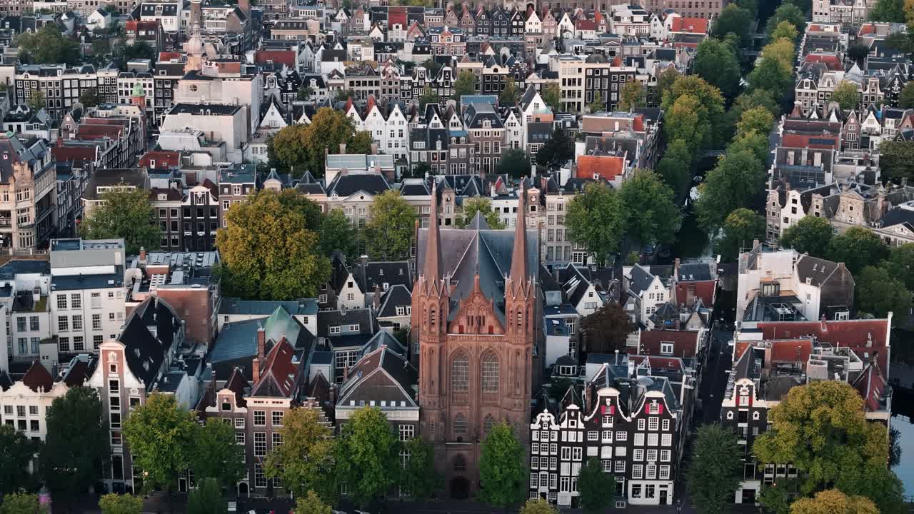 Red brick church stands among canals and houses as morning light fills Amsterdam