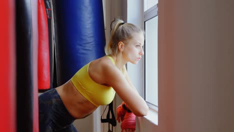 Female-boxer-looking-through-window-in-fitness-studio-4k