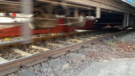 close-up shot of a grungy old railroad car running wheel on train tracks, primary suspension, brake cylinder and swing arm