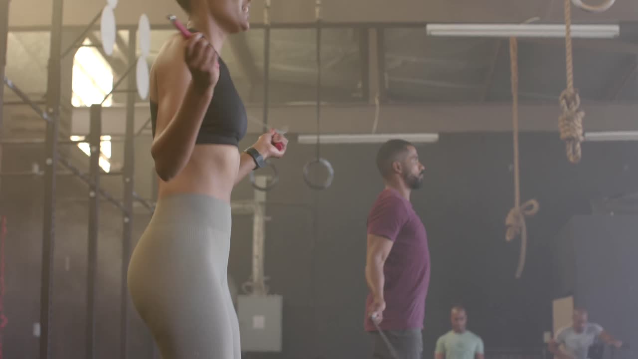 다양한 남성과 여성이 체육관에서 천천히 뛰어오르는 로프를 훈련하고 있습니다.